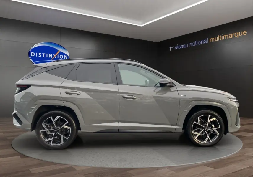 Vue de profil côté gauche d'un Hyundai Tucson gris foncé 2026, avec jantes alliage et lignes anguleuses marquées.