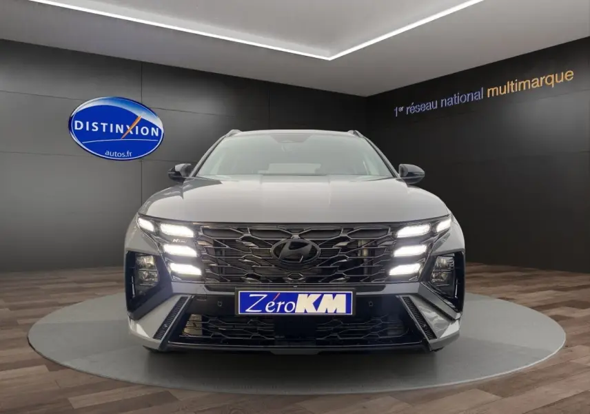 Vue avant d'un Hyundai Tucson gris foncé avec calandre noire et feux LED allumés en showroom.