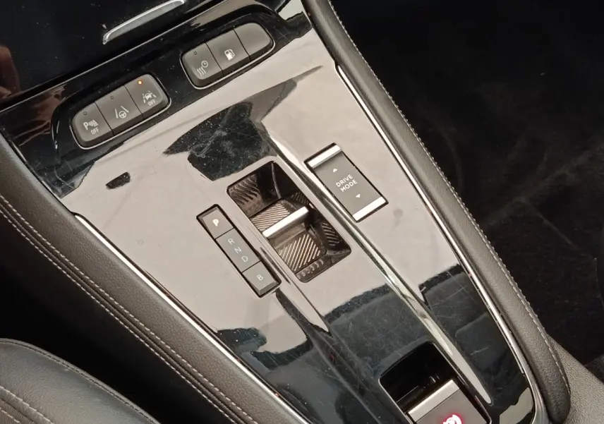 Vue rapprochée de la console centrale noire brillante de l’Opel Grandland hybride avec commandes de boîte automatique et mode de conduite.