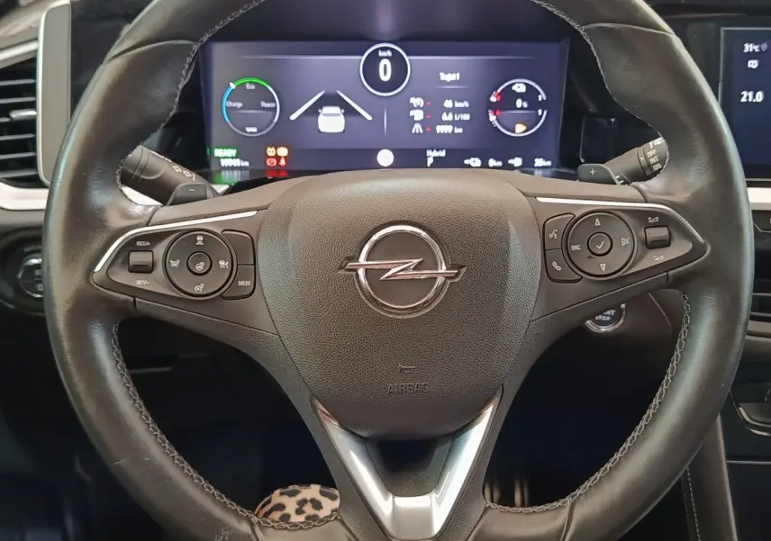 Vue rapprochée du volant cuir et alu multifonctions de l’Opel Grandland Hybride 225 ch, avec tableau de bord numérique.