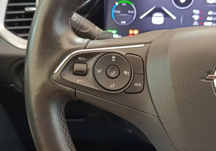 Gros plan sur le volant cuir et alu noir de l’Opel Grandland hybride 225 ch, avec commandes multifonctions visibles.