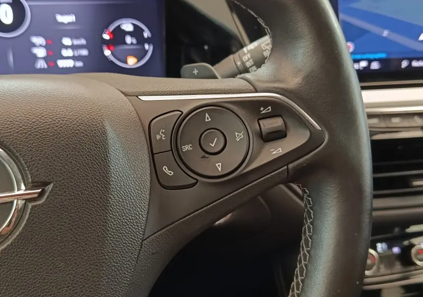 Gros plan sur le volant cuir et alu multifonctions de l’Opel Grandland hybride noir, avec commandes audio intégrées.