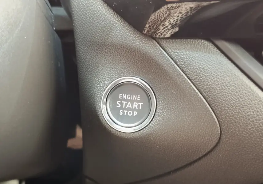 Gros plan sur le bouton démarrage moteur noir entouré de chrome dans l'habitacle d'un Opel Grandland noir 2023.