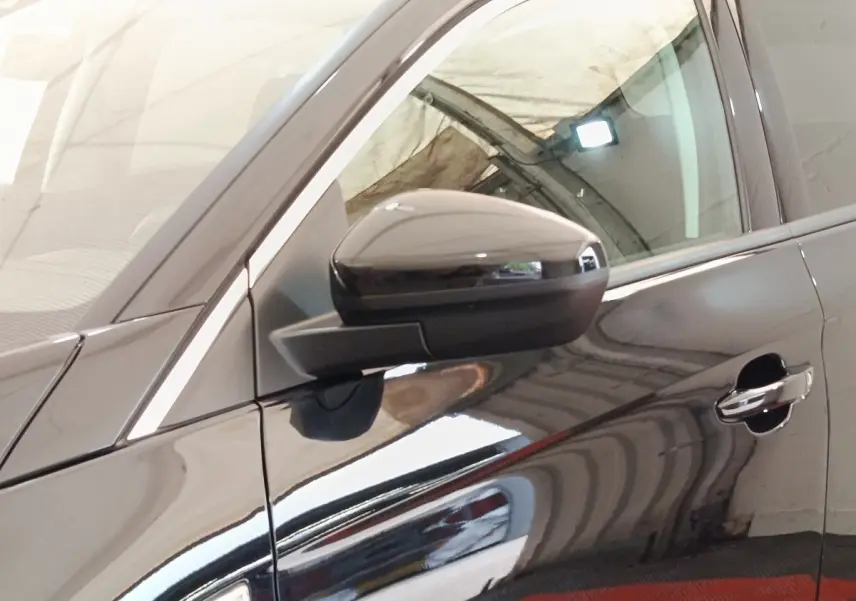 Gros plan sur le rétroviseur et la portière côté conducteur d’un Opel Grandland hybride noir brillant.