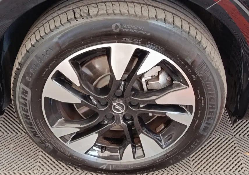Gros plan sur la jante alu bicolore et pneu Michelin du côté avant droit d’un Opel Grandland noir hybride 2023.