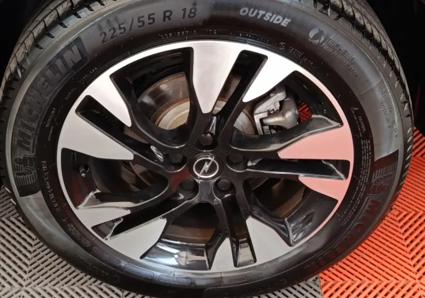 Gros plan sur la jante alu bicolore noire et argentée avec pneu Michelin du SUV Opel Grandland hybride 2023 noir.
