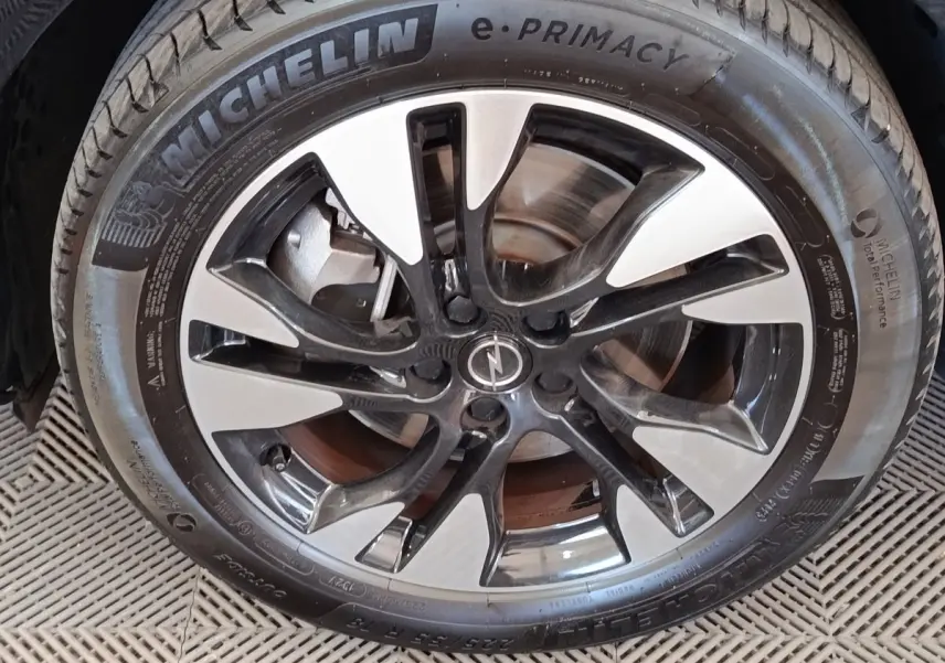 Gros plan sur la jante alliage bicolore noire et argentée d’un Opel Grandland hybride 2023, pneu Michelin visible.
