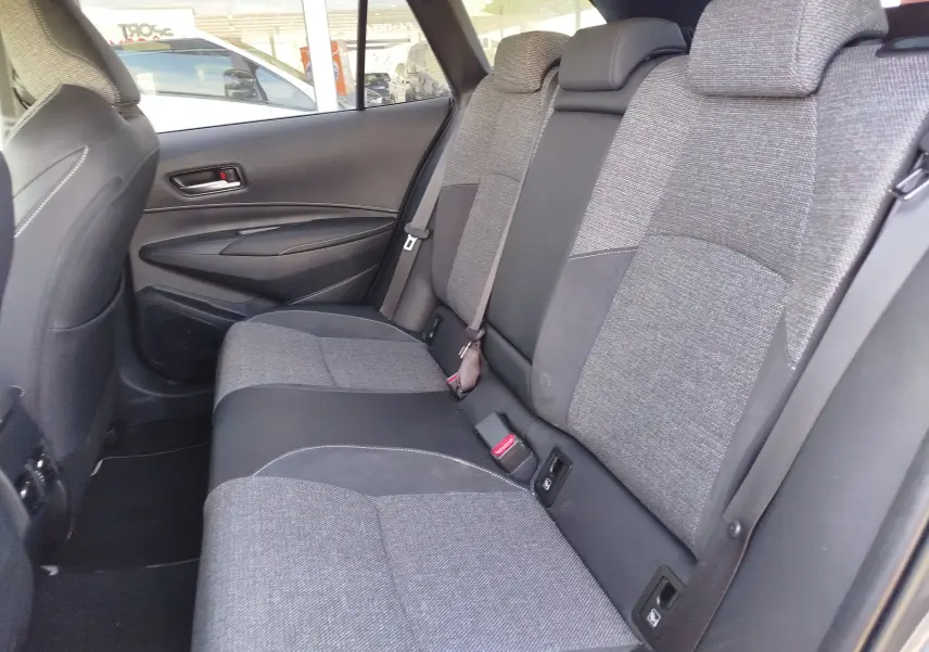 Vue latérale droite de la banquette arrière gris clair et noir de la Toyota Corolla Touring Sport 2026, tissu et cuir mêlés.