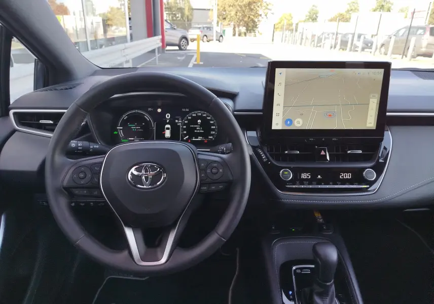 Vue intérieure du tableau de bord de la Toyota Corolla Touring Sport 2026 avec écran tactile GPS et volant multifonction noir.