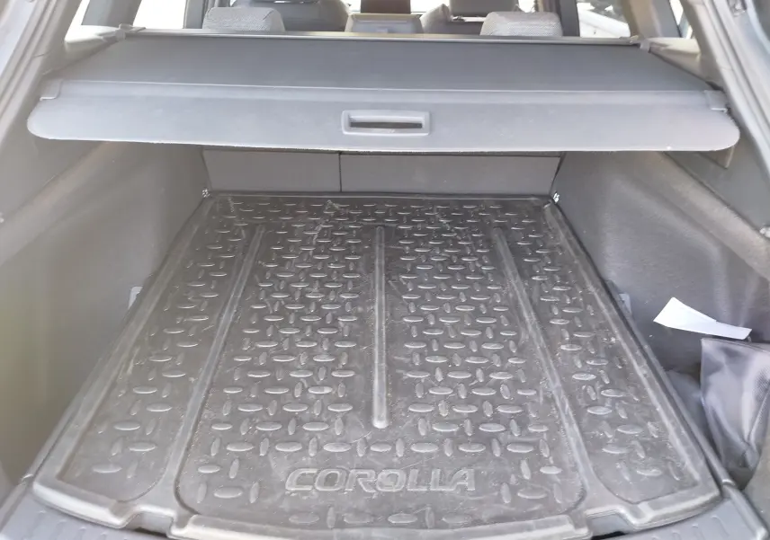 Vue intérieure du coffre de la Toyota Corolla Touring Sport 2026, tapis de protection noir marqué "COROLLA" visible.