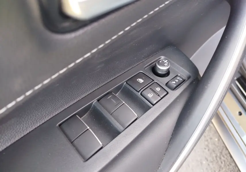 Gros plan sur les commandes de lève-vitres et rétroviseurs côté conducteur d'une Toyota Corolla Touring Sport gris Atlas.