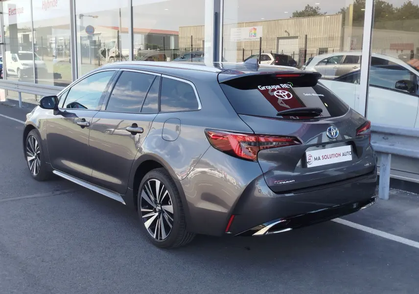 Vue 3/4 arrière droite d'une Toyota Corolla Touring Sport gris Atlas avec jantes alliage et vitres teintées.