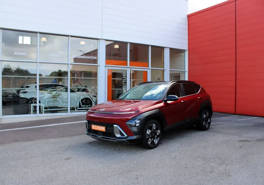 Hyundai Kona hybride rouge Ultimate métal vu en 3/4 avant droit, avec toit noir et jantes bi-ton.