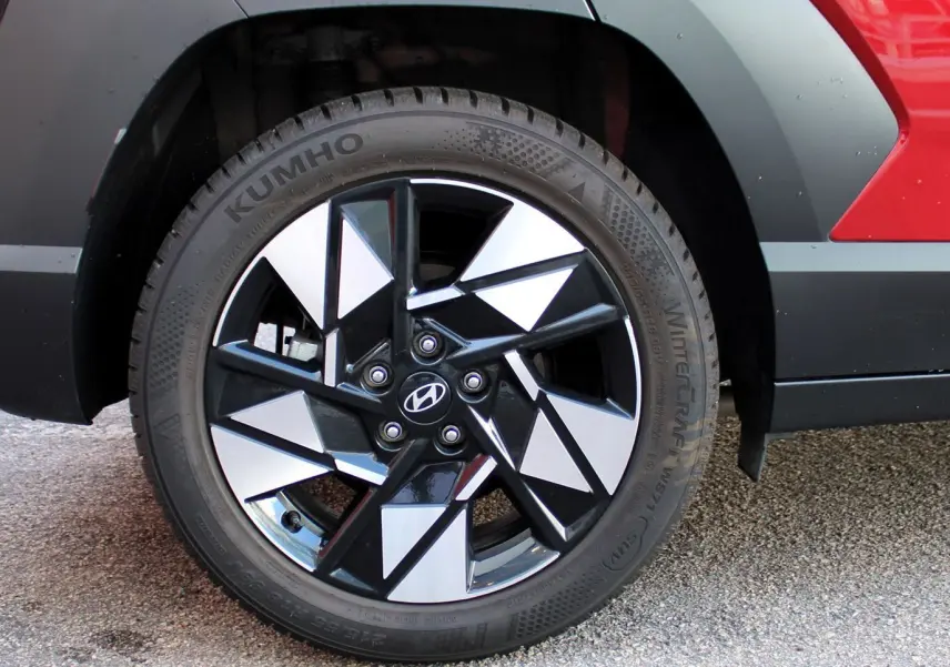 Gros plan sur la roue avant droite du Hyundai Kona 2024 rouge Ultimate Metal avec jante alliage noire et argentée.