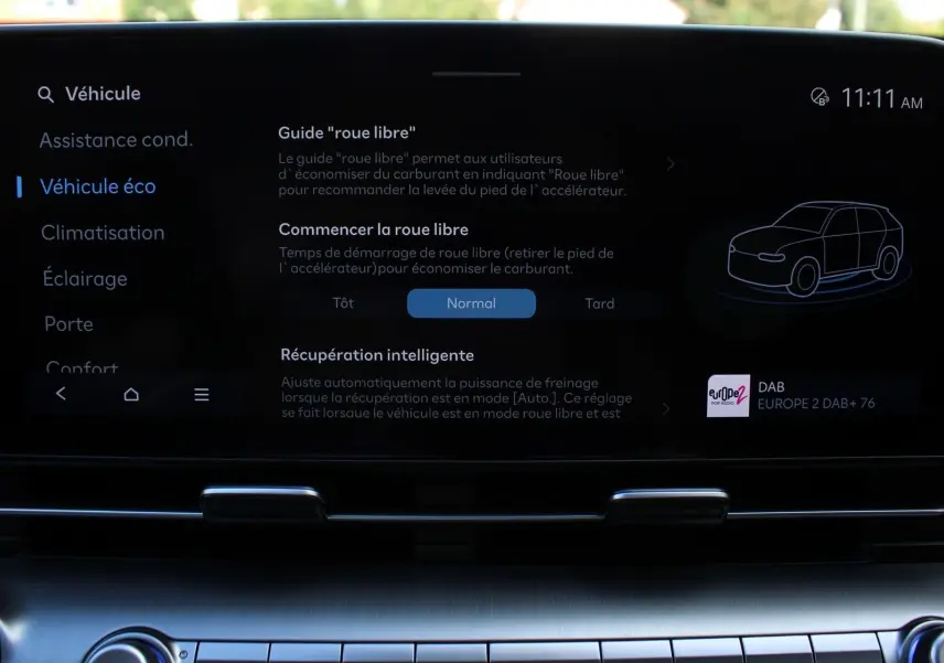 Écran tactile central du Hyundai Kona 2024 affichant les réglages du mode éco et guide "roue libre" en intérieur noir.