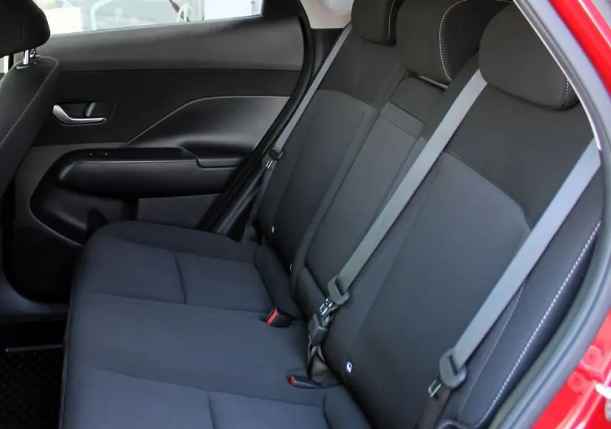 Vue intérieure côté droit des sièges arrière noirs du Hyundai Kona 2024 rouge Ultimate Metal avec ceinture de sécurité.