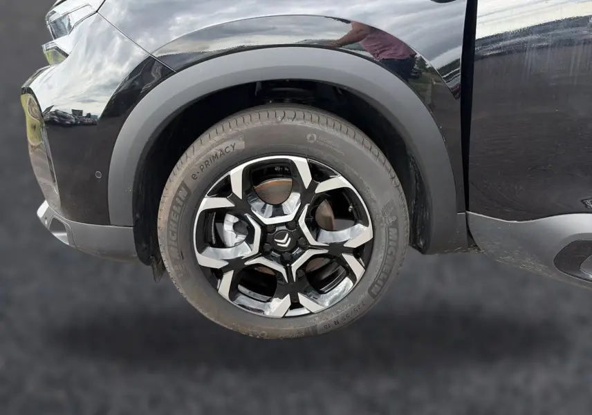 Gros plan sur la roue avant gauche noire avec jante alu bicolore du Citroën C5 Aircross 2025 hybride.