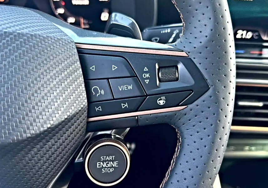 Gros plan sur le volant cuir perforé bleu fjord de la CUPRA Formentor 1.5 etsi hybrid avec commandes multifonctions et bouton start/stop.