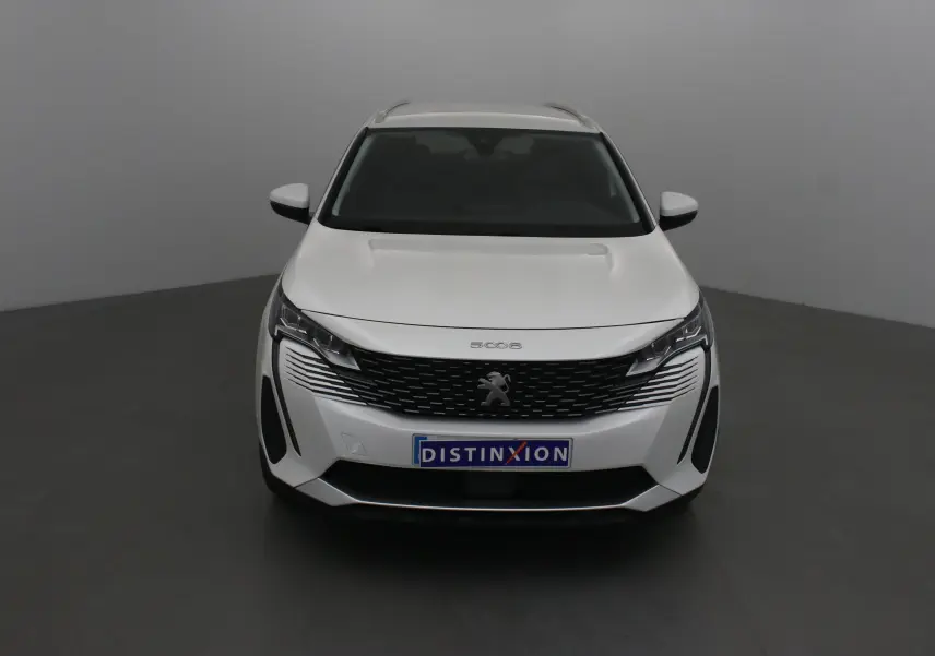 Vue frontale d'un Peugeot 5008 blanc nacré avec calandre noire et logo lion distinctif sur fond neutre.