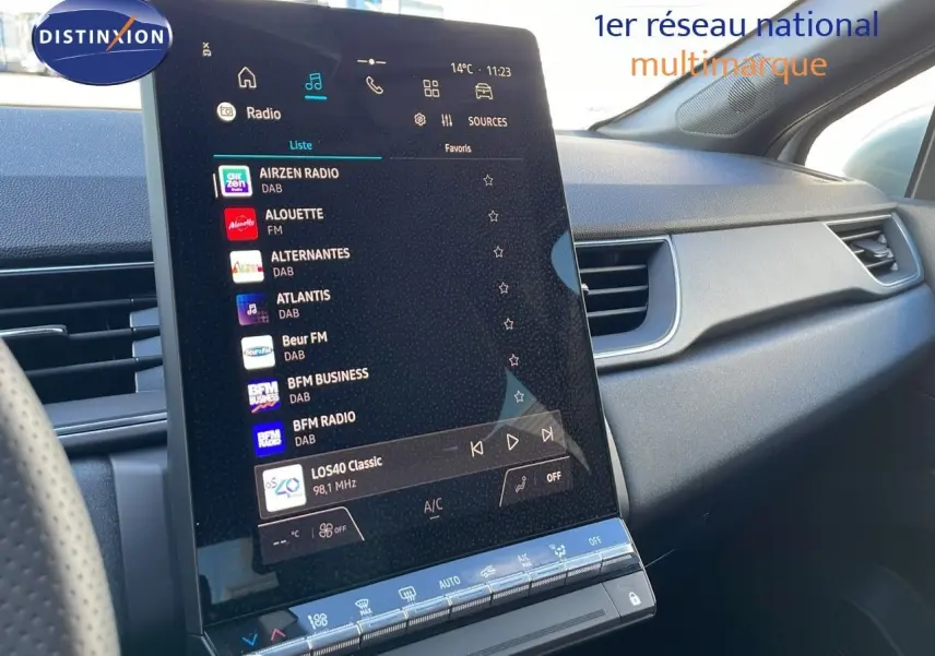 Vue intérieure du tableau de bord du Renault Captur E-Tech blanc nacré, écran tactile central affichant les stations radio.