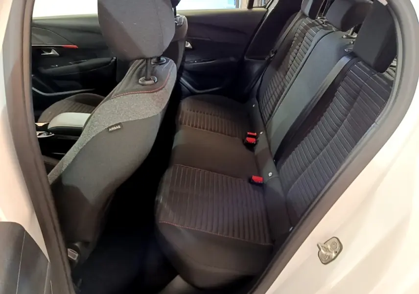 Vue intérieure côté arrière droit de la banquette noire avec surpiqûres rouges de la Peugeot 208 Electrique Active Business blanche.