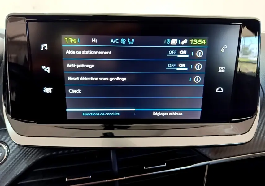Écran tactile central affichant les réglages d'aide à la conduite dans une Peugeot 208 électrique blanche, vue intérieure.