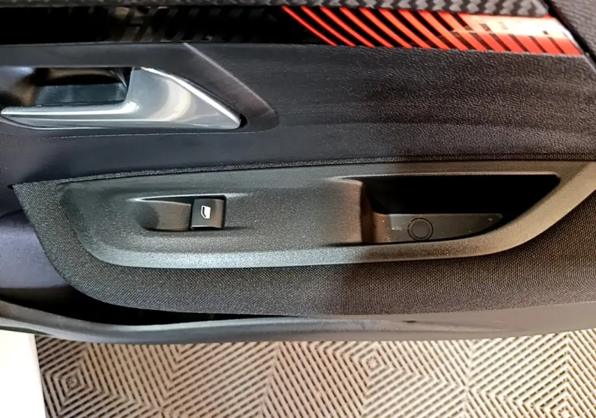 Gros plan sur la poignée intérieure et le bouton de lève-vitre côté conducteur d'une Peugeot 208 Electrique Active Business.