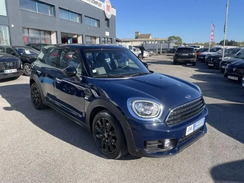 Vue 3/4 avant d'une MINI Countryman Cooper D 2018 bleu foncé avec jantes noires, stationnée en extérieur.