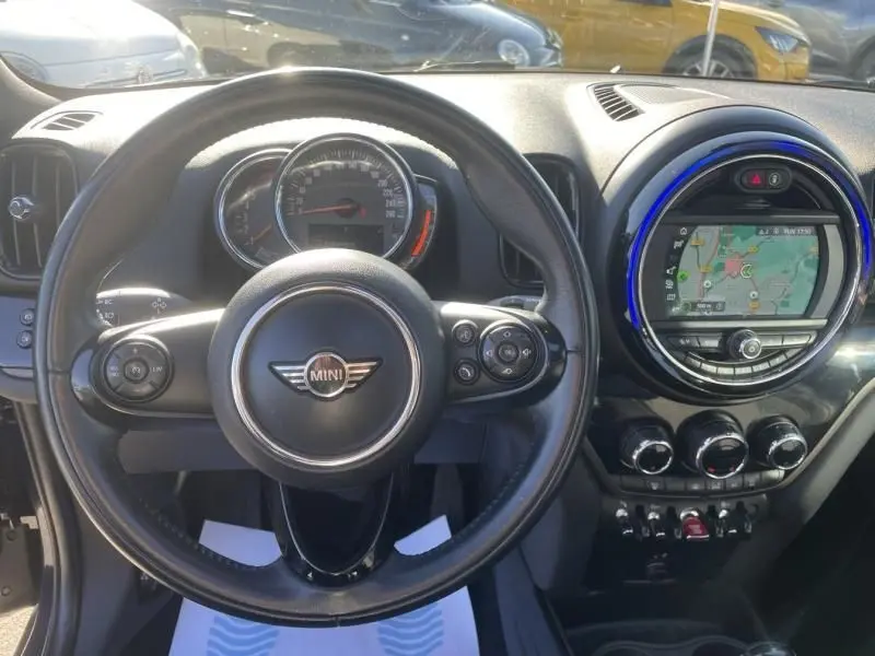 Vue intérieure centrée sur le volant MINI d’un Countryman bleu 2018 avec écran tactile et compteur circulaire.