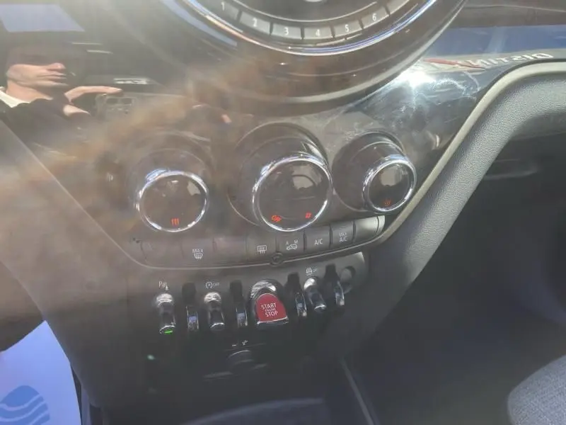 Gros plan sur la console centrale du MINI Countryman bleu 2018, avec commandes de climatisation et bouton start/stop rouge.