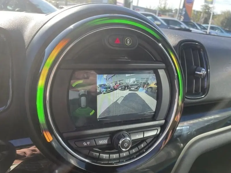 Vue rapprochée du tableau de bord du MINI Countryman 2018 bleu, avec écran de caméra de recul et éclairage circulaire coloré.