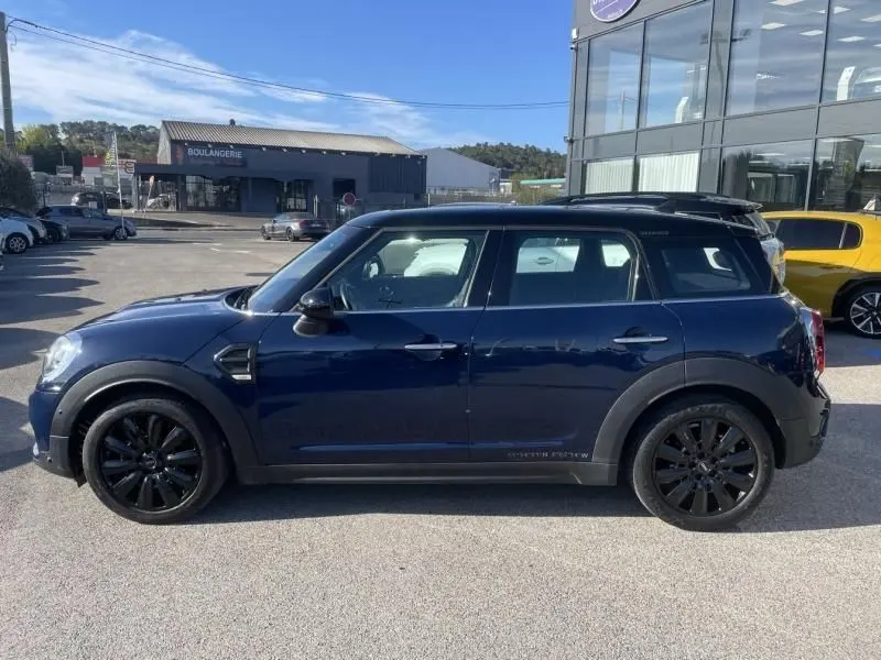 Vue de profil côté gauche d'une MINI Countryman Cooper D bleu foncé avec jantes noires, stationnée en extérieur.