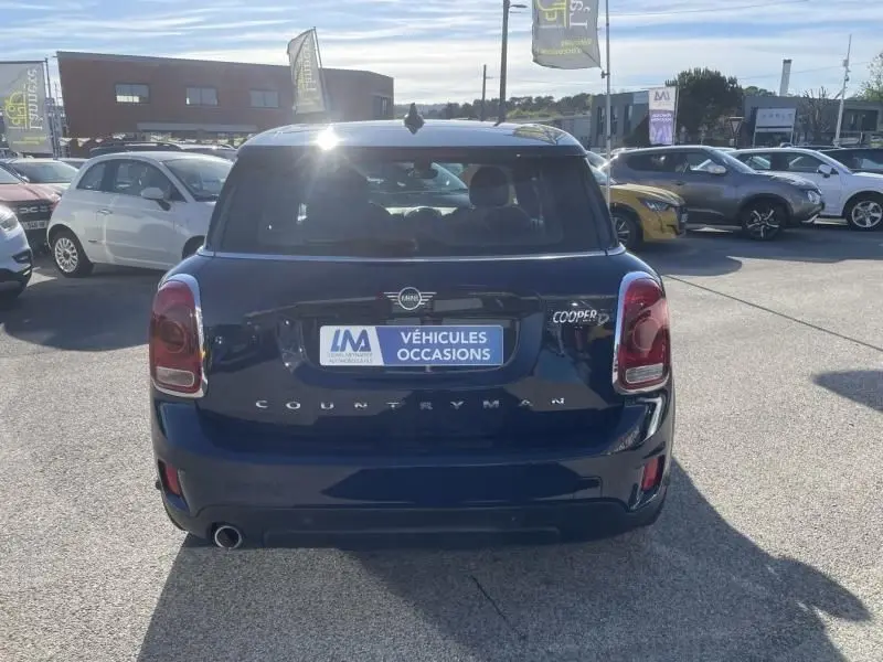 Vue arrière d'une MINI Countryman Cooper D bleu foncé, avec logo et plaque "Véhicules Occasions" visible en plein jour.