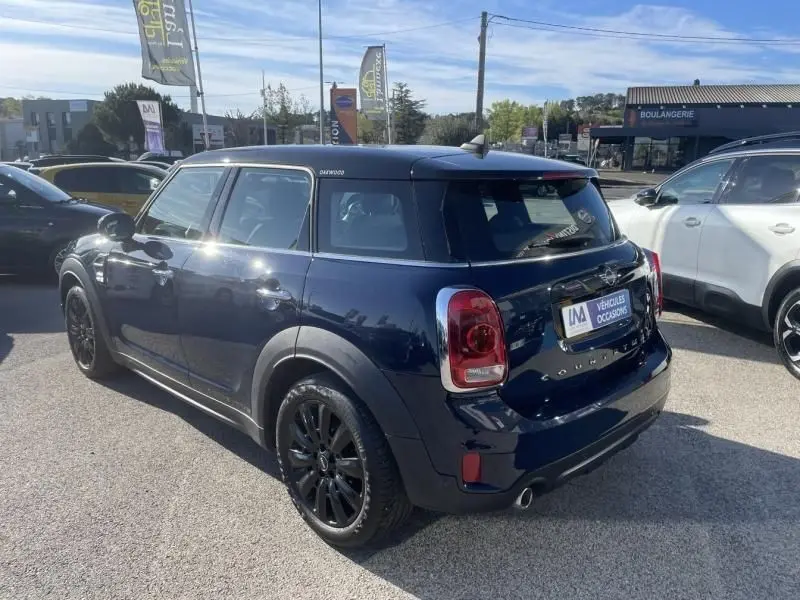 Vue 3/4 arrière droite d'une MINI Countryman Cooper D bleu foncé avec jantes noires, en extérieur sur parking.