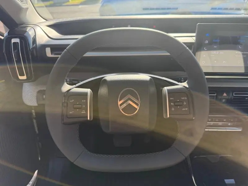 Vue rapprochée du volant noir de la Citroën C3 électrique 2025 avec commandes intégrées et tableau de bord digital.