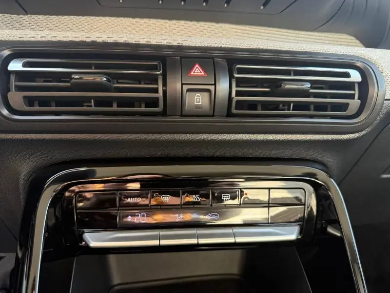 Vue rapprochée du tableau de bord noir de la Citroën C3 électrique 2025, avec commandes climatisation et aérateurs horizontaux.