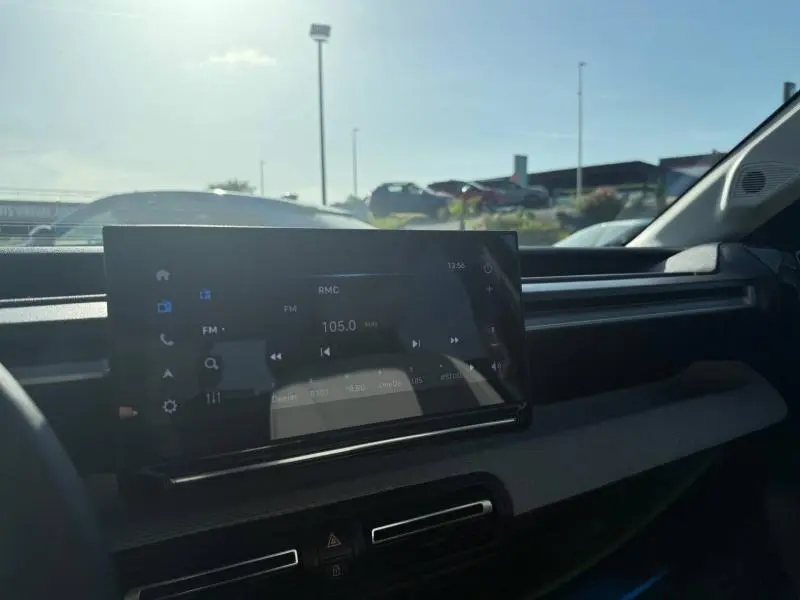 Vue intérieure du tableau de bord de la Citroën C3 électrique 2025, écran tactile affichant une radio FM, ambiance sombre.