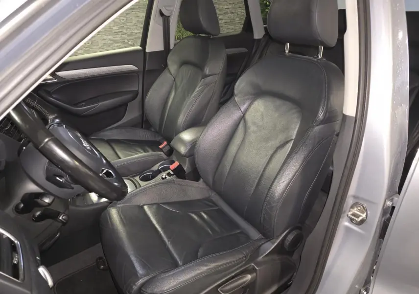 Vue intérieure côté conducteur de l'Audi Q3 2016 avec sièges cuir Nappa noirs et accoudoir central gris.