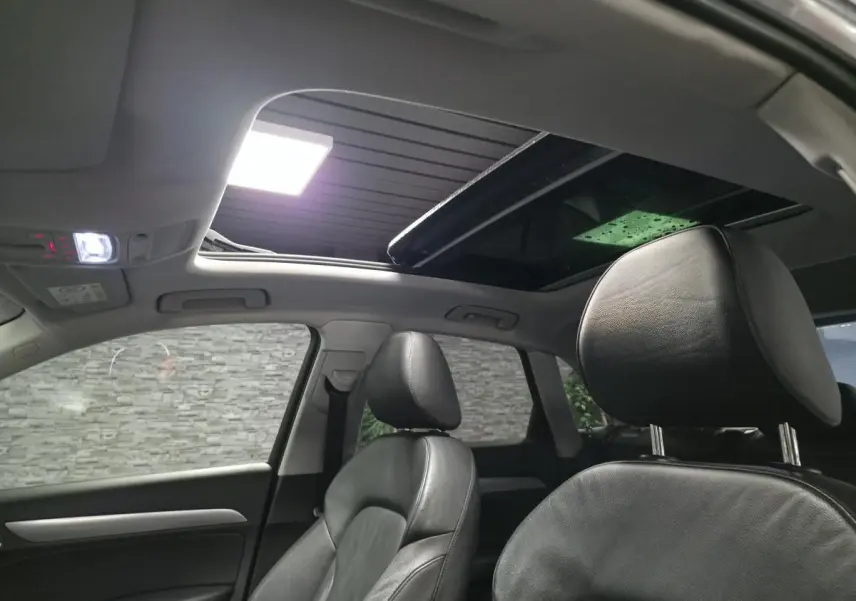 Vue intérieure avant droite de l'Audi Q3 2016 avec sellerie cuir noire et toit ouvrant panoramique ouvert.