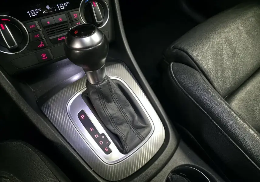 Gros plan sur la console centrale d’un Audi Q3 2016 avec levier de boîte automatique et sellerie cuir noire.