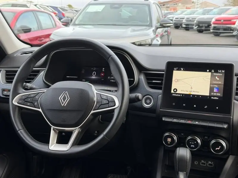 Vue intérieure du tableau de bord du Renault Arkana 2025, avec volant multifonction et écran tactile de navigation allumé.