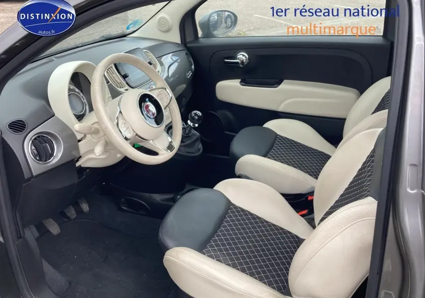 Vue intérieure côté conducteur de la Fiat 500 gris, avec volant beige, sièges bicolores et tableau de bord moderne.