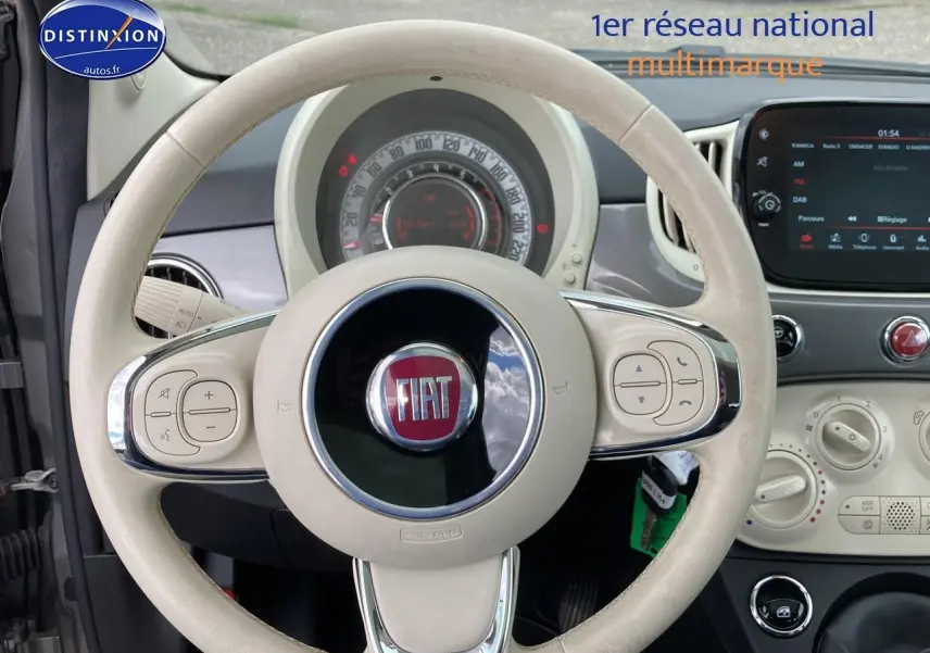 Vue intérieure centrée sur le volant beige de la Fiat 500 2022 avec tableau de bord et écran tactile visible.