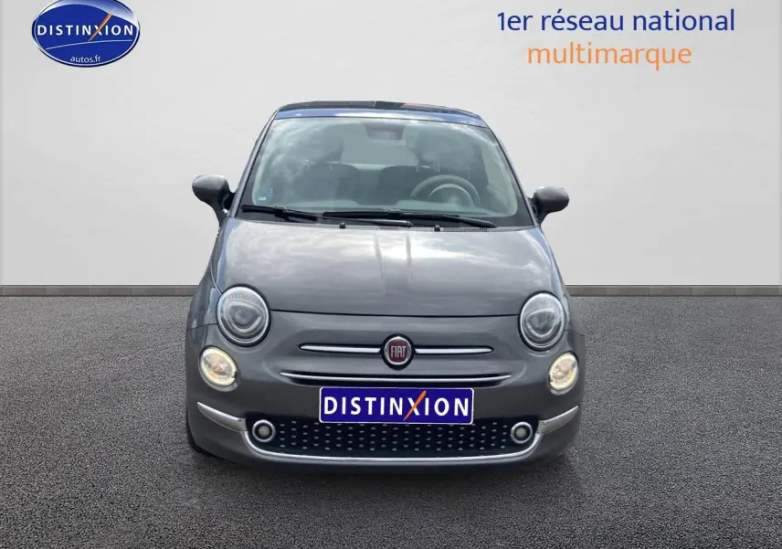 Vue frontale d'une FIAT 500 gris métallisé avec phares ronds et toit panoramique en verre visible.