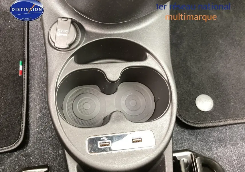Gros plan sur la console centrale de la Fiat 500 gris avec porte-gobelets et prises USB visibles.