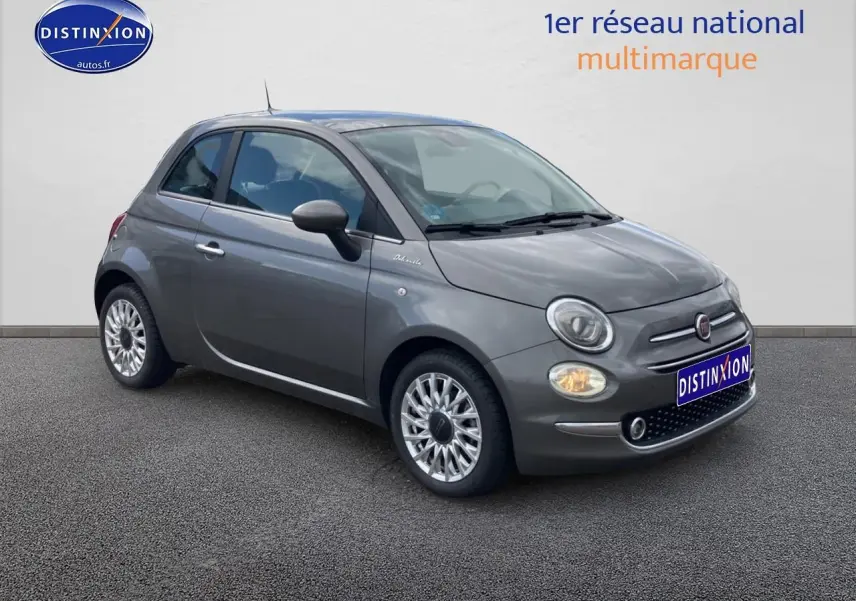 Fiat 500 gris vue 3/4 avant droit, avec jantes alu et phares allumés sur fond neutre.