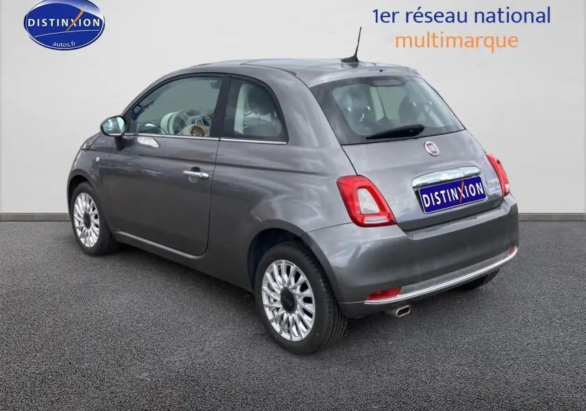 Vue 3/4 arrière droite d'une Fiat 500 gris métallisé avec jantes alu et toit panoramique en verre.