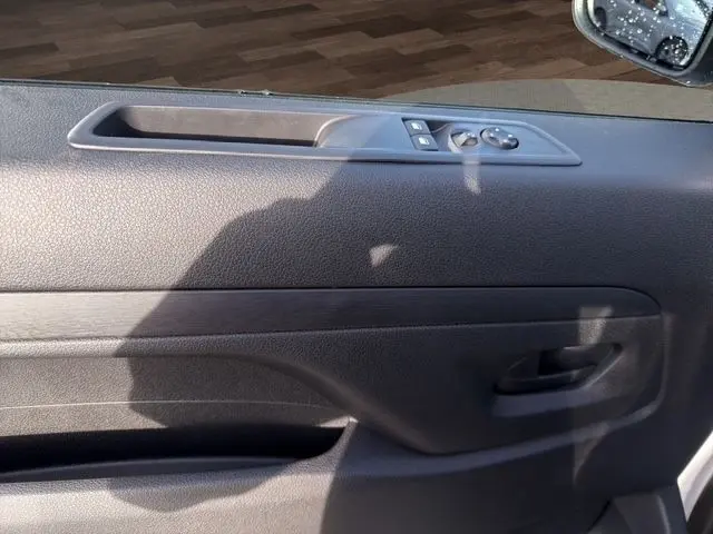 Vue rapprochée de la porte côté conducteur du Citroën Jumpy blanc, montrant les commandes de vitres et rétroviseur.