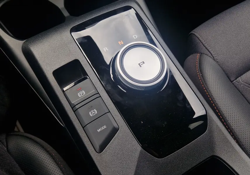 Gros plan sur la molette de boîte automatique et commandes de mode, intérieur noir avec surpiqûres orange du MG3 1.5L Hybrid+ 2026.
