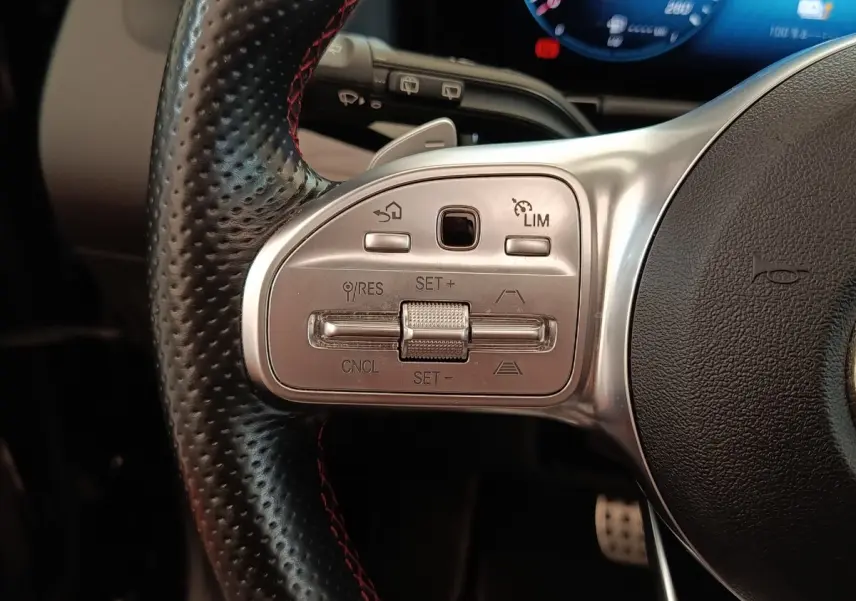 Gros plan sur le côté gauche du volant cuir perforé noir avec commandes de régulateur de vitesse du Mercedes GLA 250 e AMG Line 2021.